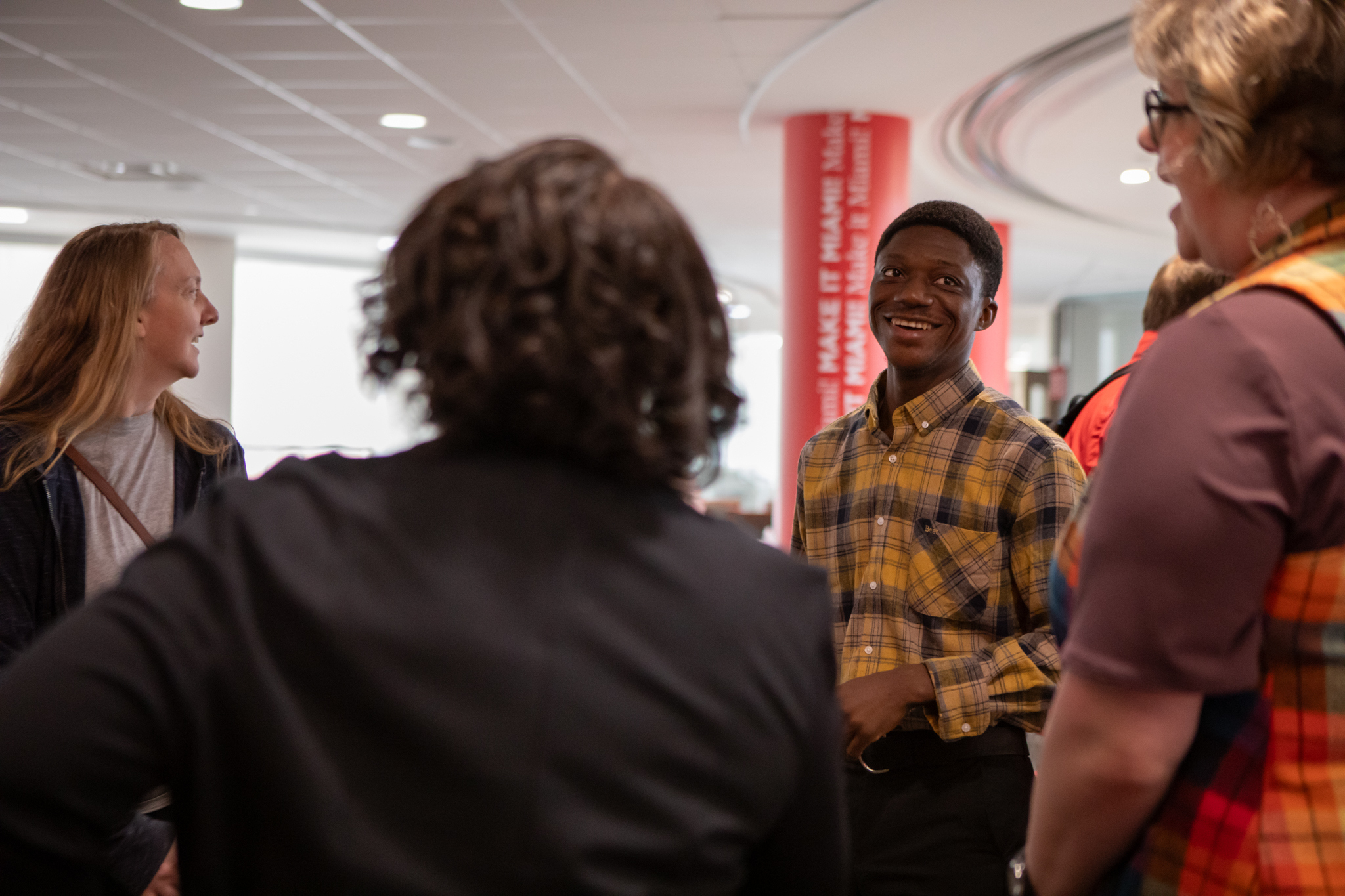 A student smiles while speaking with three people at the 2024 Graduate Education Resource Fair.