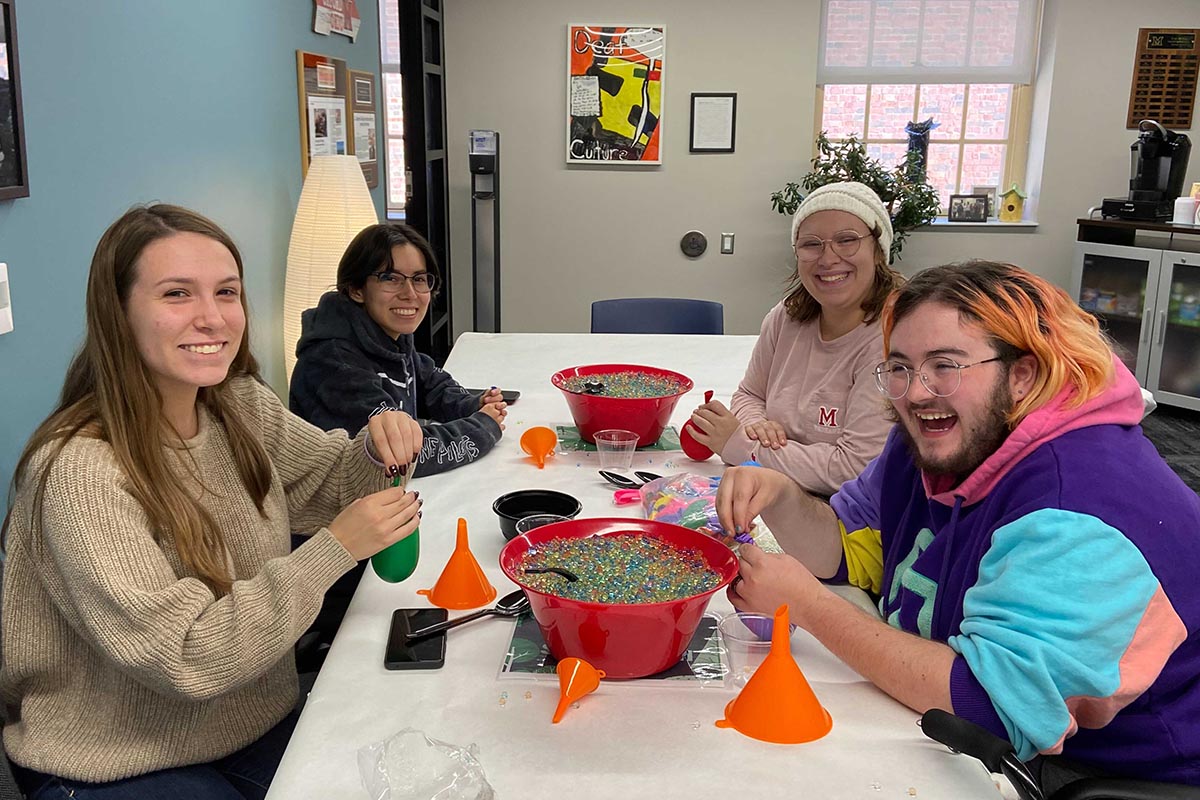 Four students sitting at a table working on an art project
