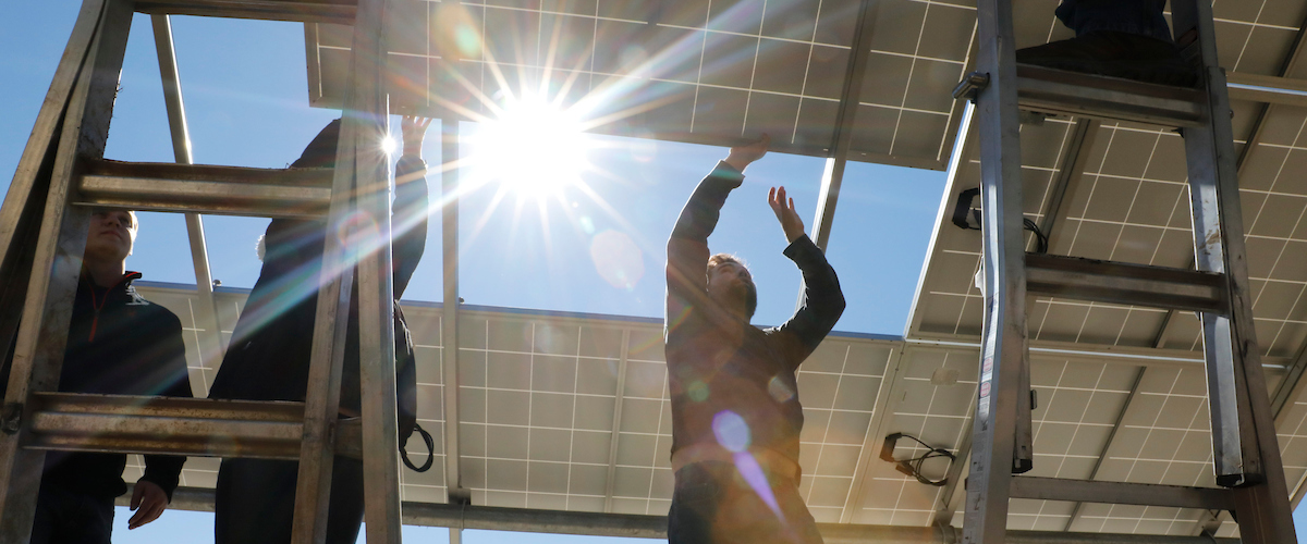 The sun backlights the scene as Institute for Food students build a solar array