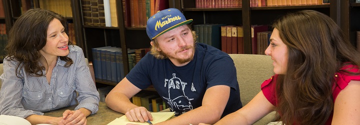 Students having a discussion with their professor in a campus library