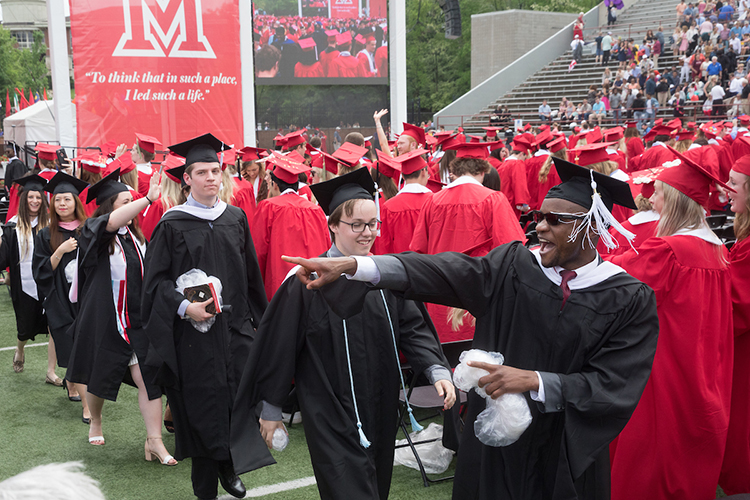 Graduate students walk down the center row at the end of the ceremony