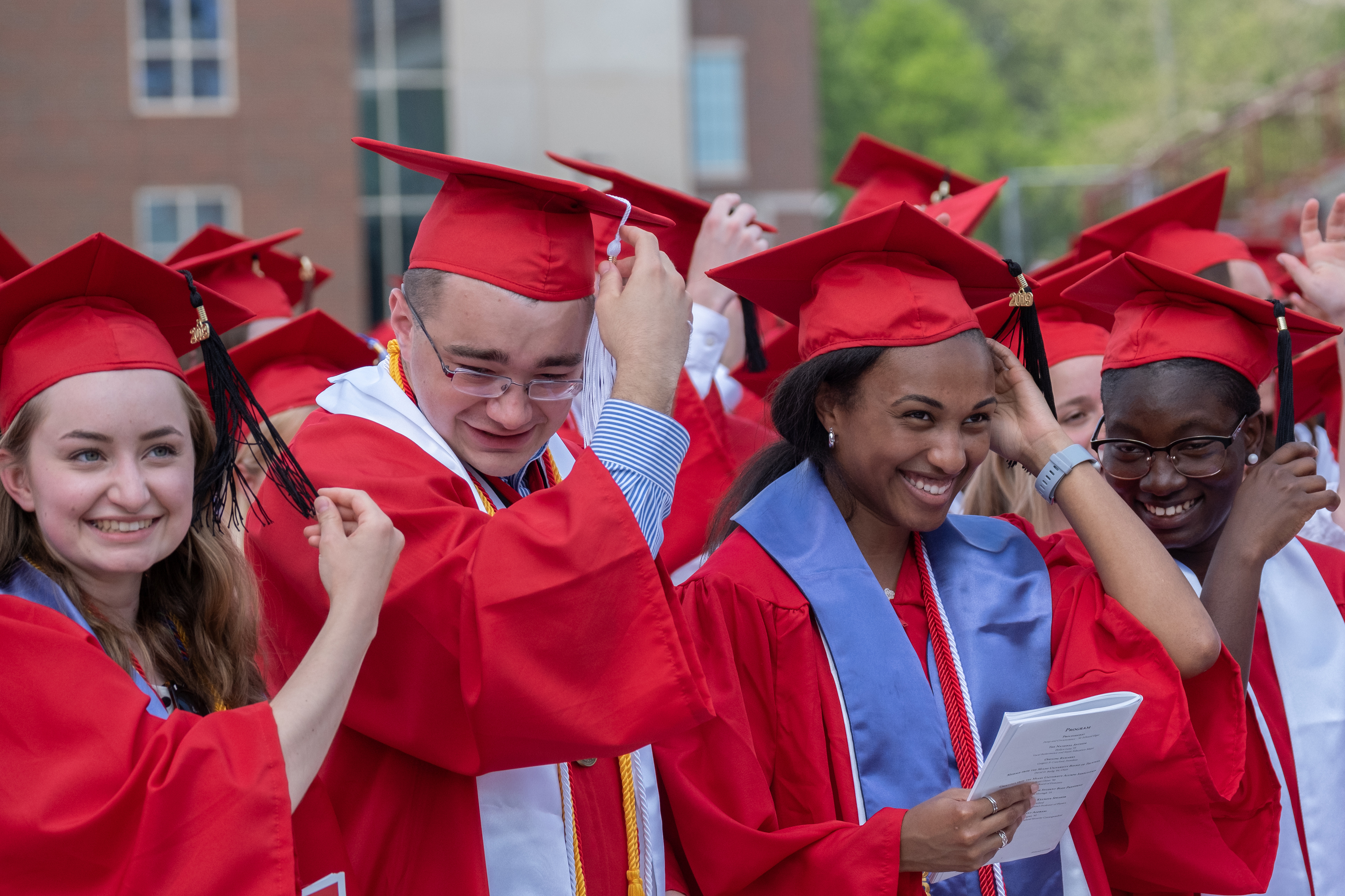 Group of graduates moving tassel on cap from left to right