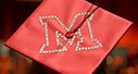 Red graduation cap with the Miami beveled M spelled with sparkly rhinestones