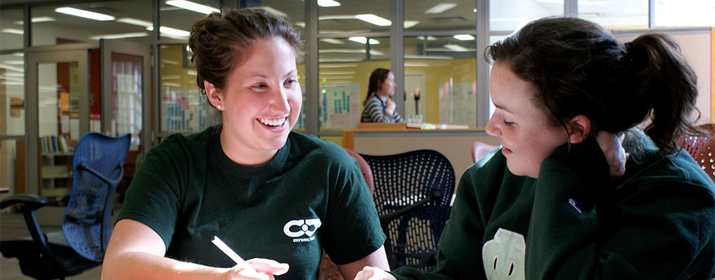 Two girls working at a table in the writing center
