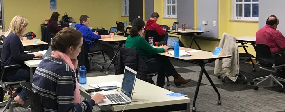 Students sitting at tables and working in a large room