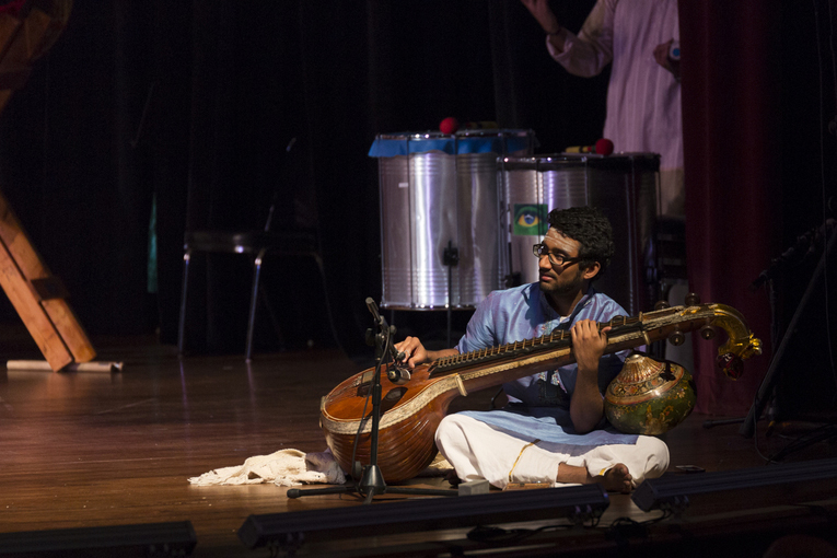 A man sits on stage and plays a sitar