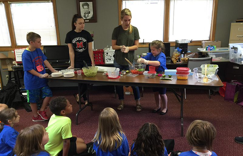 Miami nutrition students assist youngsters making fresh tomato salsa and guacamole.