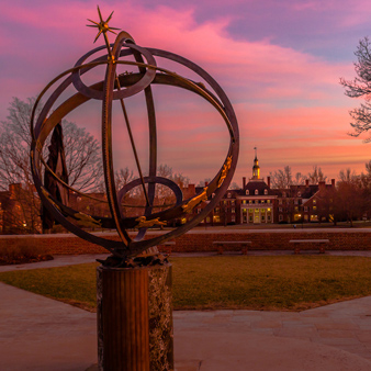 The Tri Delt Sundial on campus against a sunset sky of pink and purple