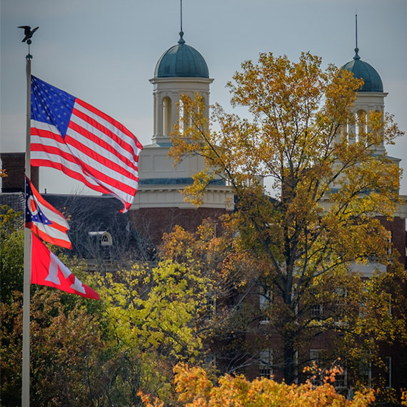 The U.S., Ohio, and Miami flags fly in front of Harrison Hall, the home of Miami's Menard Family Center