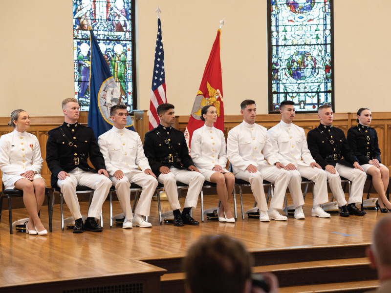 2023 Commissioning Ceremony graduates sitting in a line on the stage.
