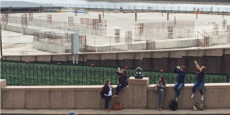 Students raise their devices to take photos in front of a London construction site