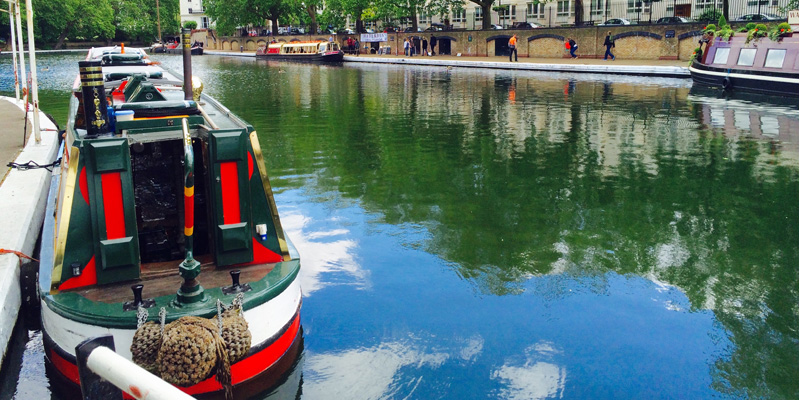 London Regents Canal. A red and white boat is in the foreground.