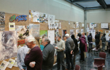 faculty and students looking at writings and drawings posted on wall in cage gallery