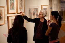 A faculty member gestures toward an artwork as students look on