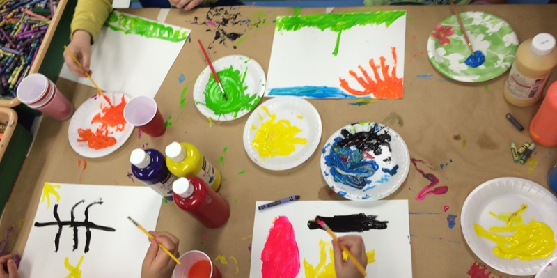 Children at a table work on watercolor paintings