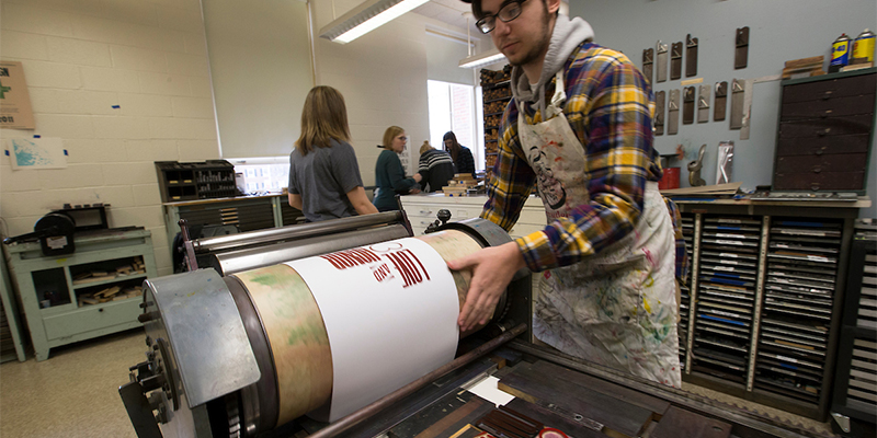 A student operates the letterpress. The project displays the words 'love and honor'