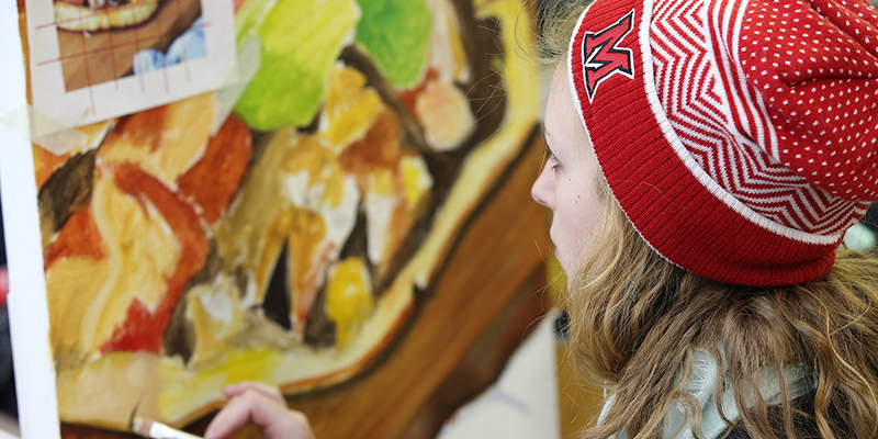 A student in a red knit Miami hat participates in a painting class
