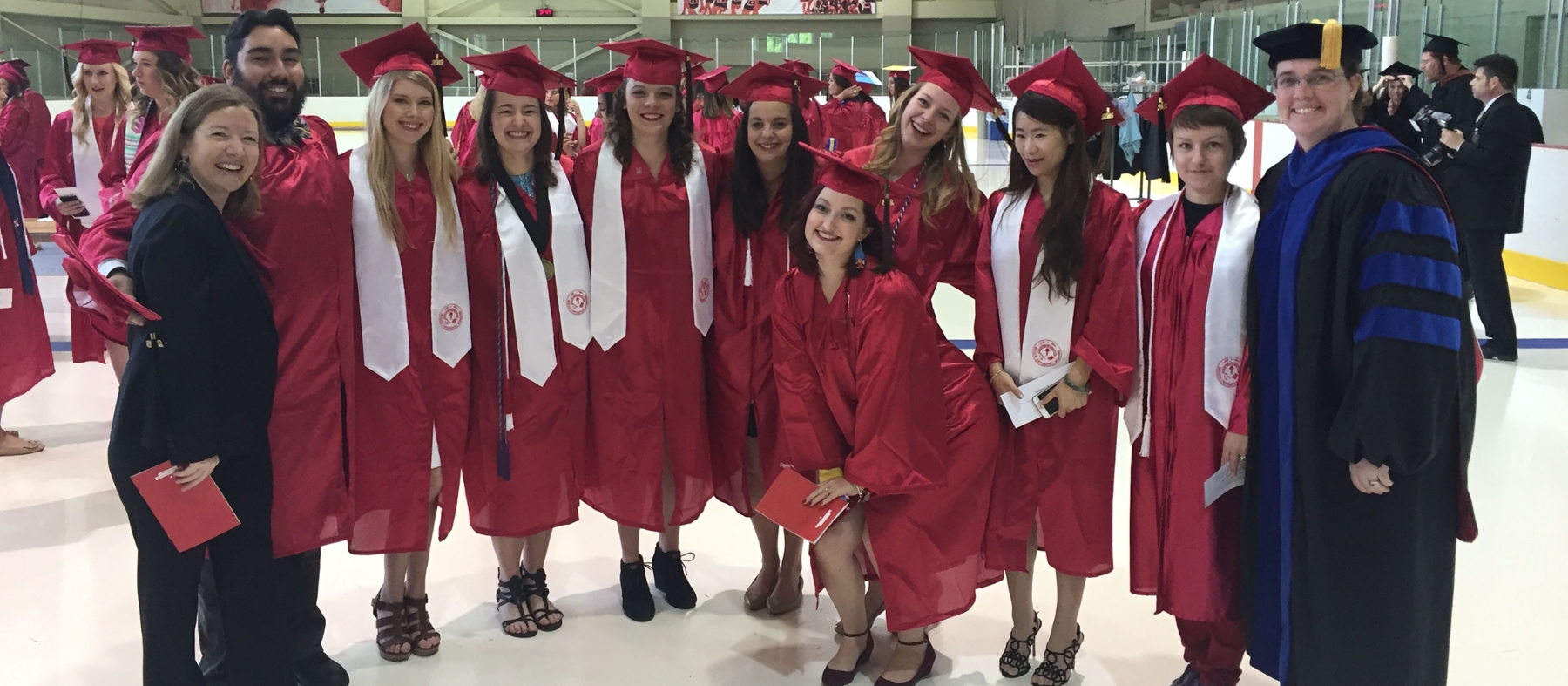 Recent art education graduates pose at Goggin Ice Arena
