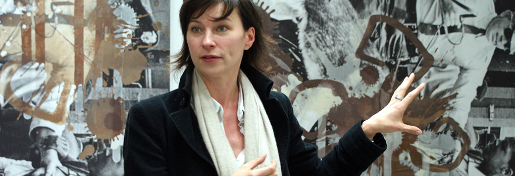 A museum curator delivering a talk gestures toward an artwork