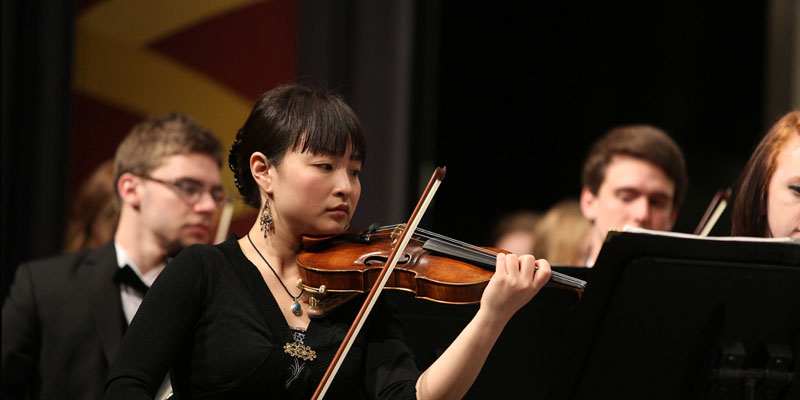 Closeup of violinists performing in the Miami Symphony Orchestra at Hall Auditorium