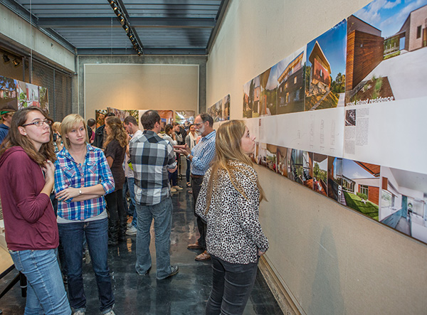 Students and faculty observe art on the walls of the Cage Gallery