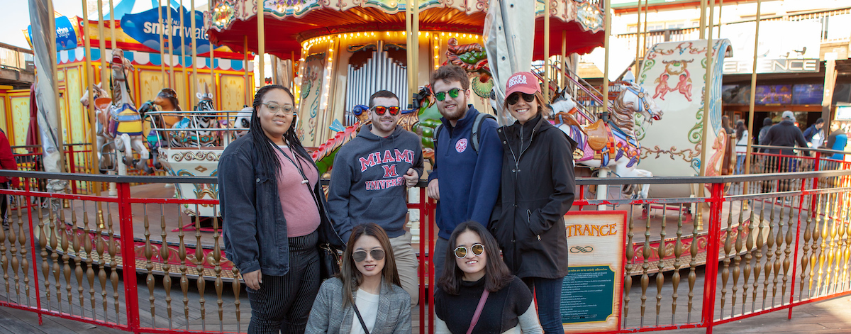 Students pose near a carousel on Fishermans Wharf
