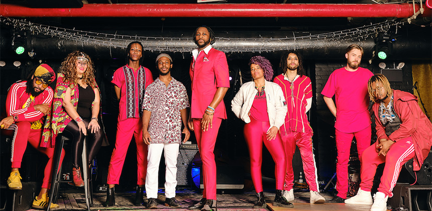 Mwenso and The Shakes band members posing on a stage wearing hot pink