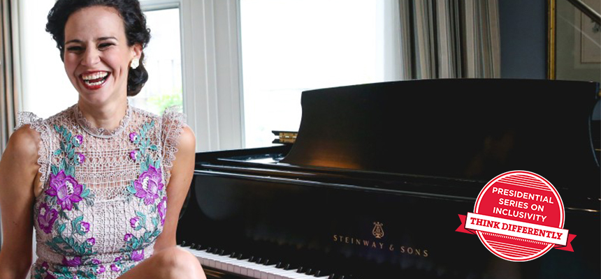 Mandy Gonzalez laughs as she sits facing away from a grand piano. Badge: Presidential Series on Inclusivity
