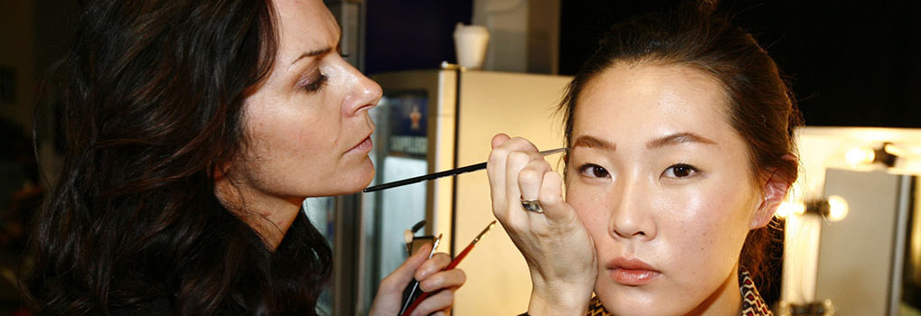 A makeup artist applies makeup to an actress