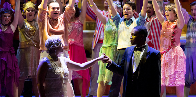 A couple holding hands pose in front of a crowd in a scene from The Wild Party