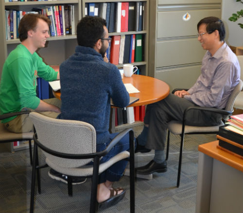 Dr. Zhou chatting with students in his office