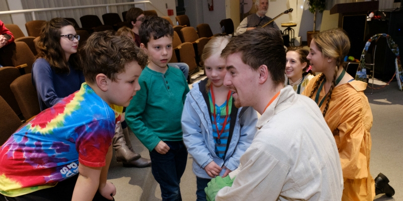 student sits in a circle with children laughing