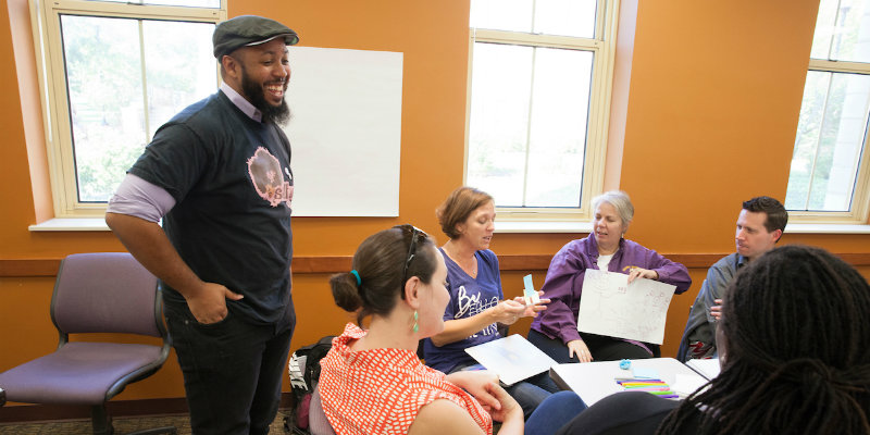professor stands at front of classroom interacting with students