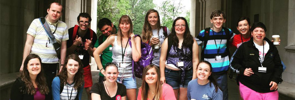 educational psychology students take a group photo under an arch