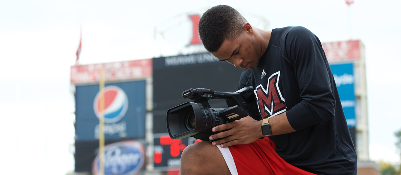 SLAM student filming at football game
