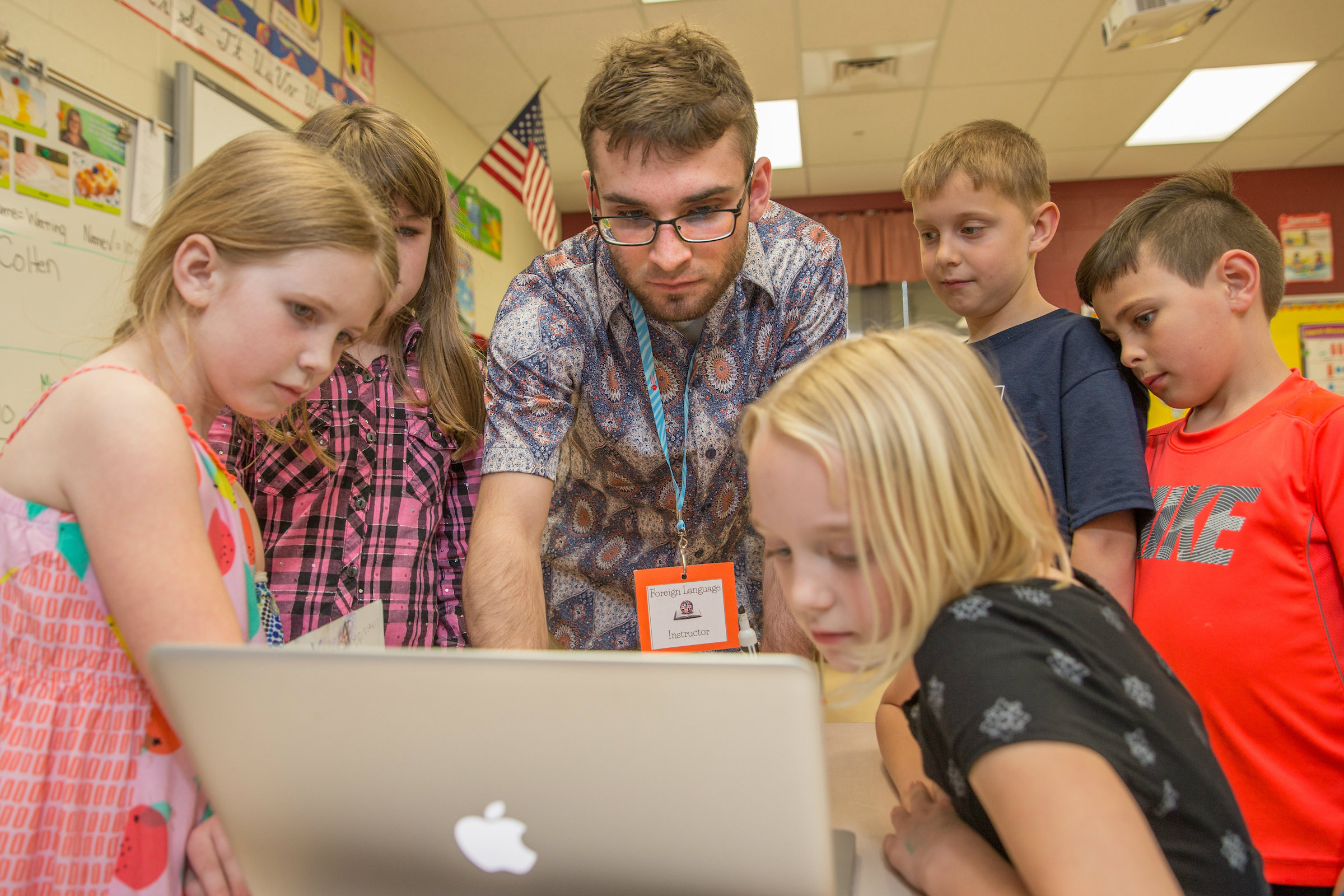 student teacher and students are looking at computer together