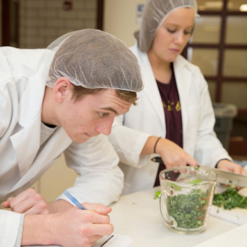 two student preparing food in a kitchen lab