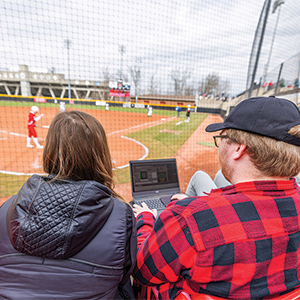 students doing sport analytics during a baseball game