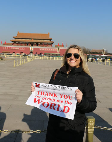 Student traveling abroad, holding sign that says