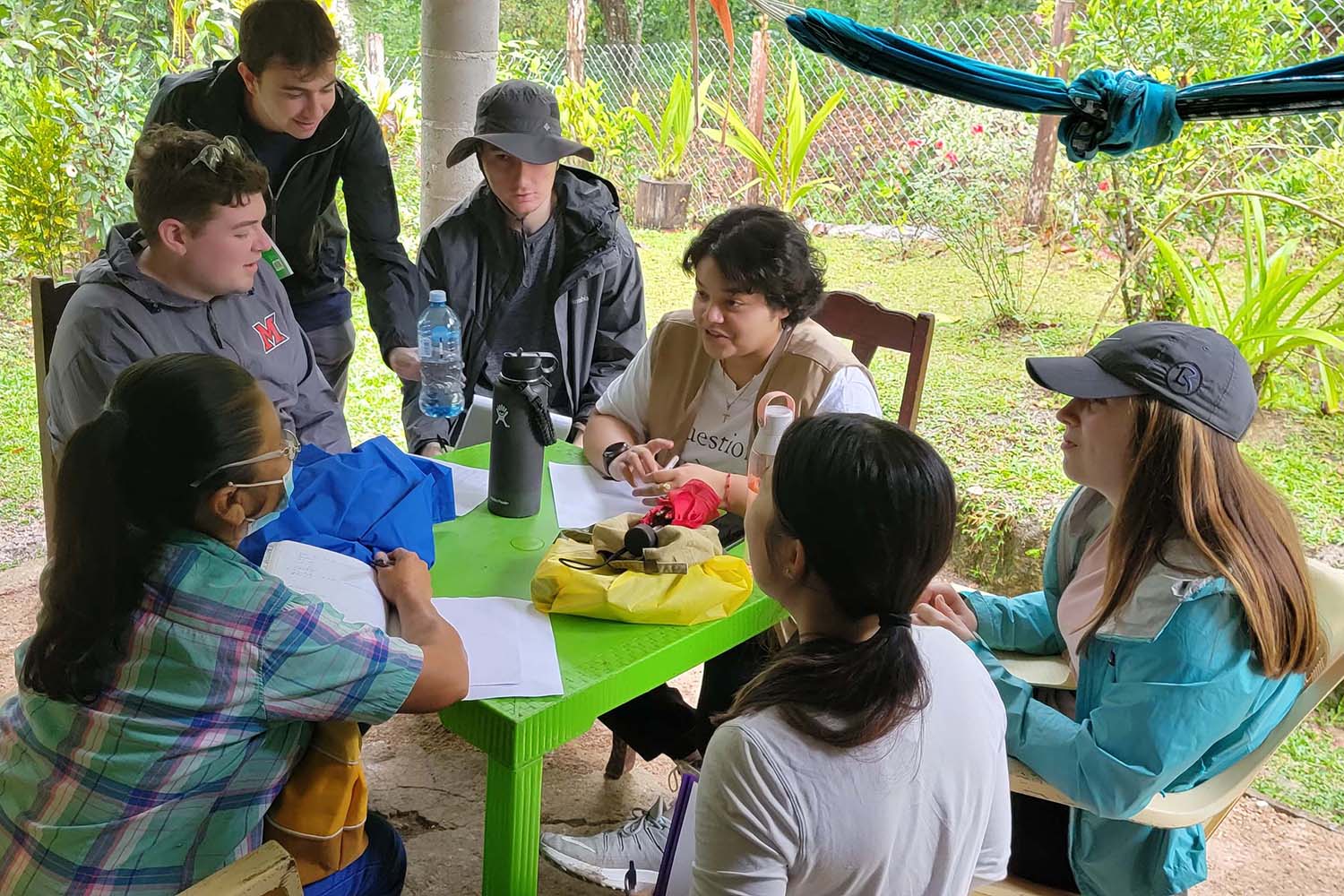 Students talk with a villager at a table