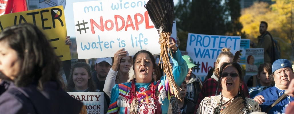 Standing Rock Native American Tribe march in Washington DC in 2017; woman holding sign that says #NoDAPL water is life