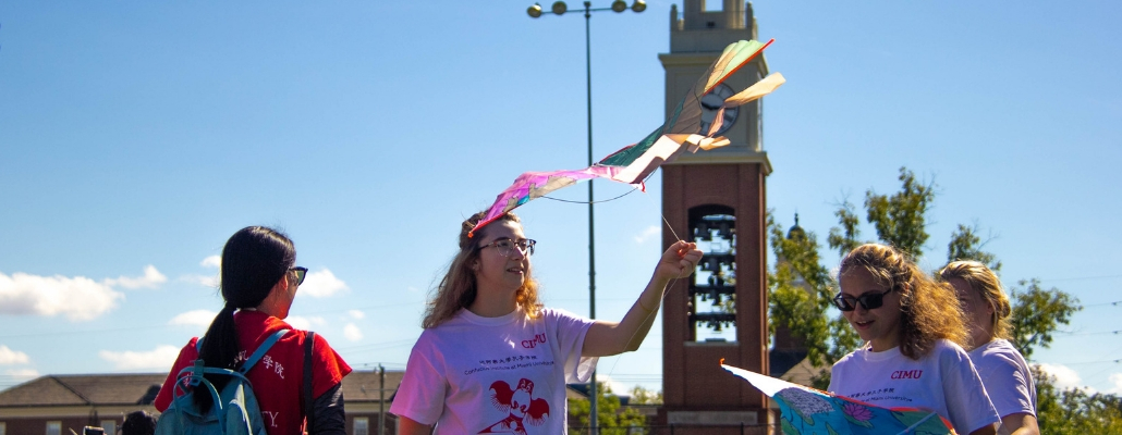 student from local school flying a kite on cook field, tower in background