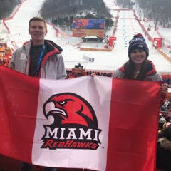 Students holding up a Miami Redhawks flag at the Olypics.