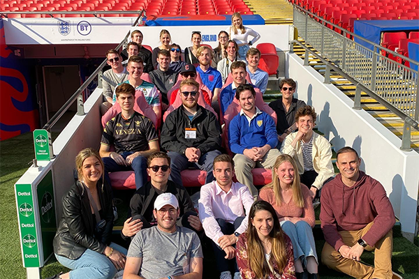 Miami students and program director pose on the steps of a soccer stadium in England