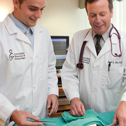 A pre-med student working with a doctor, learning the tools of his trade