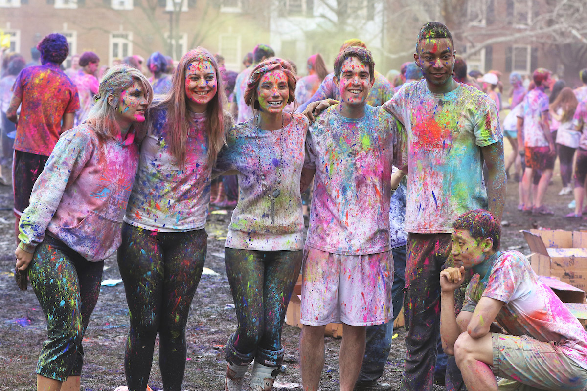 Group of students covered in multi-colored powders during Holi event