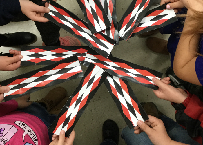 a group of people gathered in a circle holding holding myaamia ribbon 