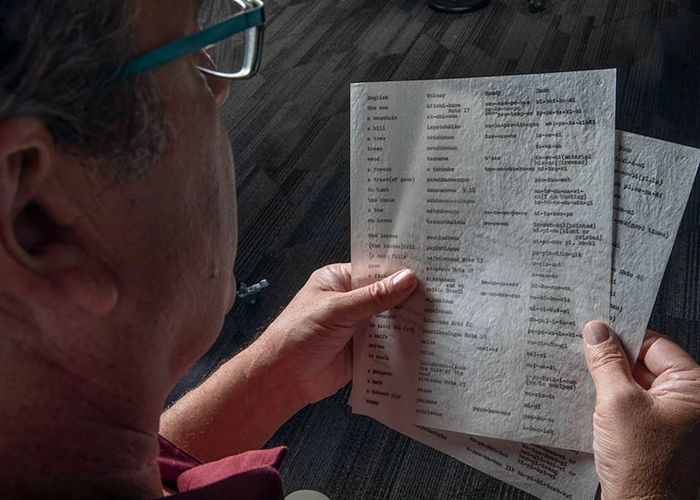 a person looking at myaamia language writing on paper
