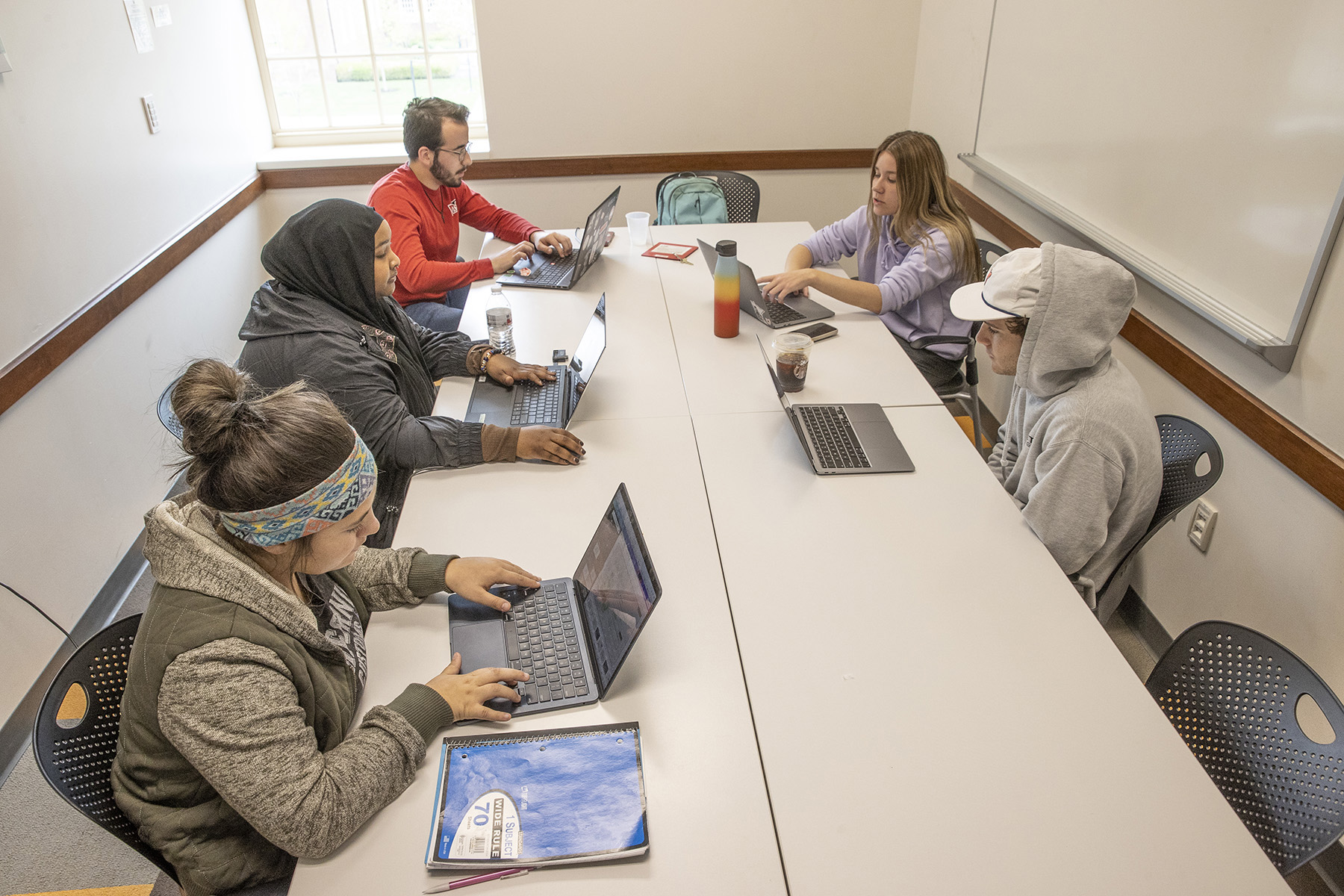 Five students sit around a conference table together.