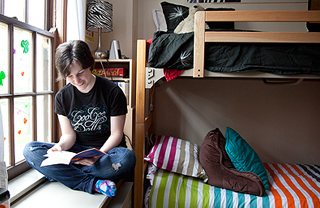 A student in a dorm room reading.